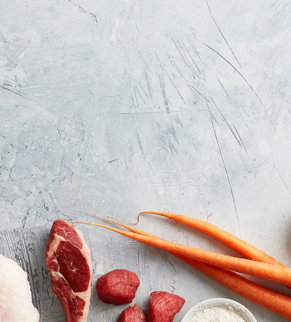 Instinct, the Raw Brand logo and images of raw meat and vegetable ingredients used to make pet food.