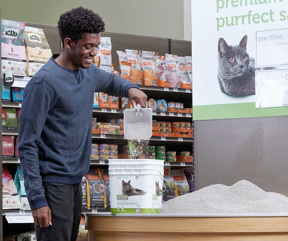 Man scooping cat litter into refillable So Phresh container